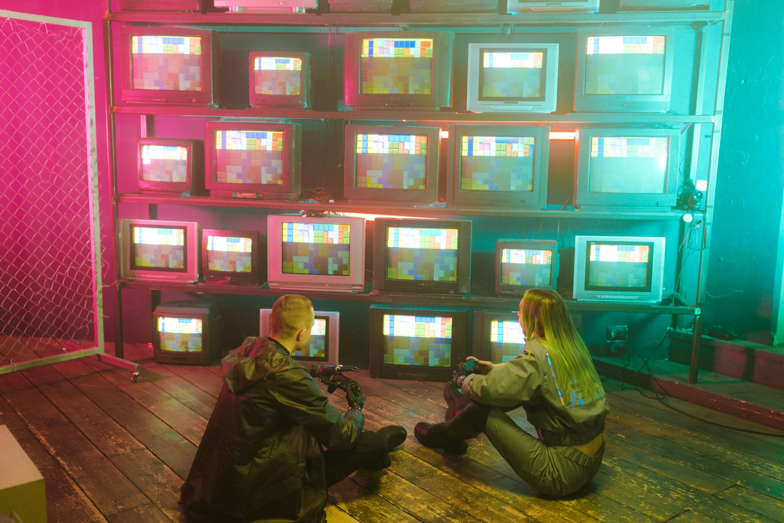 A cyberpunk inspired setting featuring two people with retro TVs displaying colorful test screens.